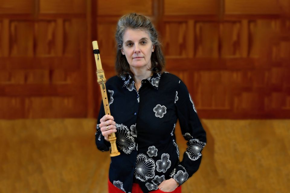 A woman wearing a black shirt with white patterns holding a chalumeau